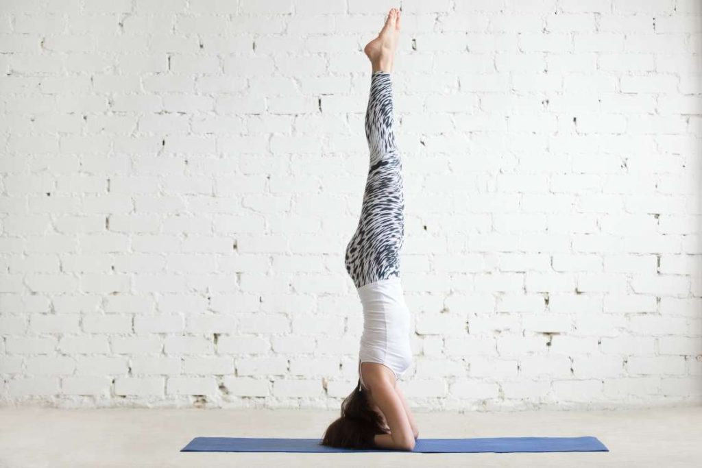 Smiling woman doing Baddha Konasana in Salamba Sirsasana B yoga pose · Free  Stock Photo